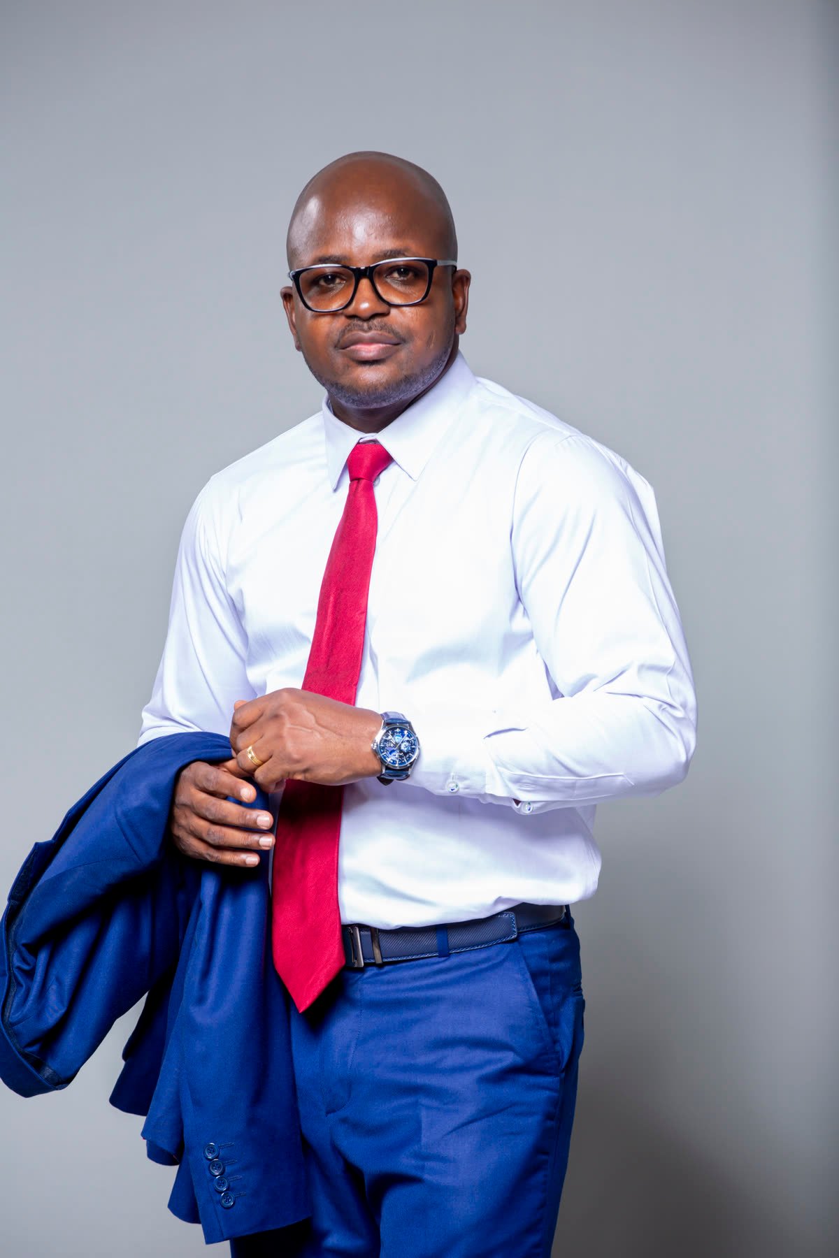 Jean Cyrille Bado, portrait studio en costume bleu marine et cravate bordeaux